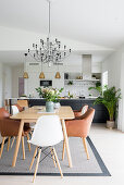 Esstisch mit Klassikerstühlen in offenem Wohnraum mit Küche im Hintergrund