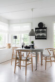 Designer chairs with fur seat cushions around traditional table in front of windows