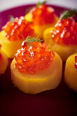 Baked potato slices with salmon caviar and dill, close-up