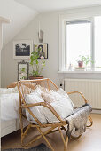 Rattan bench with cushions at foot of bed in bedroom with black-and-white photos on wall