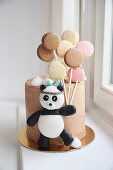A children's birthday cake decorated with a panda and macaroons