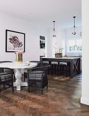 Black wicker chairs on white baluster table in front of open kitchen
