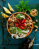 A bowl with cannellini beans, aubergine mousse, tomatoes, fennel and cashew nuts