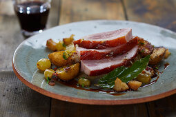 Leg of suckling pig with fried potatoes and grapes