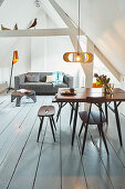 Sofa and dining area in open-plan interior below pitched roof