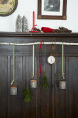 Candle lanterns made from tin cans and bunches of conifer branches hung from birch branch