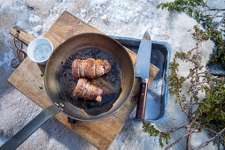 A winter barbecue: elk roulade in a pan in the snow (Norway)