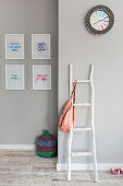 Rustic wooden ladder used as coat stand in grey hallway