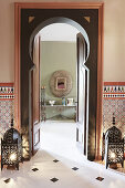 Door frame flanked by lanterns on floor and view of console table below mirror on wall