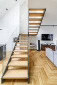 Staircase with glass balustrade used as partition in open-plan interior