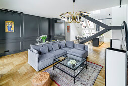 Sofa set, glass coffee table and dark, panelled wall in elegant interior