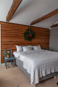 Doppelbett mit Häkeldecke vor Holzwand im Schlafzimmer