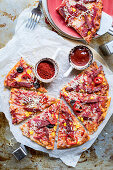 Pikante Pizza mit Würstchen, Mais und Oliven