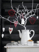 Decorations hung from branch painted white in coffee jug