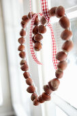 Heart-shaped garland of hazelnuts in window