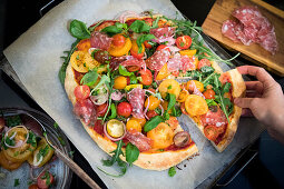 Eating Pizza with tomatoe salad with truffle salami