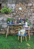 Eclectic collection of bottles, glasses and containers in front of stone wall in garden