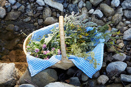Freshly collected wild herbs in a willow basket with a blue-white cloth