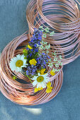 Sommerliches Wiesenblumensträußchen zwischen Kupferdrahtrollen