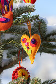 Snow-covered fir tree decorated with handmade felt pendants