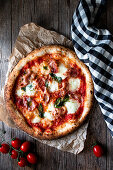 Delicious pizza with ham and mozzarella cheese checkered towel on wooden background