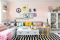 Graues Übereck-Sofa mit dekorativen Kissen in Wohnzimmer mit rosa Wand