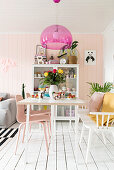 Pink pendant lamp providing a splash of colour above white dining table