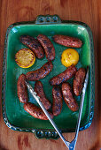 Ceramic tray with grilled sausages and lemon