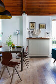 Dining table with black and gold pendant lamps below arched wooden ceiling