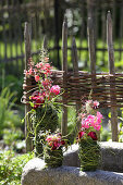 Geraniums and coleus in vases decoratively wrapped in leaves and grasses