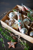 Christmas baubles in box, larch twig and star-shaped biscuit