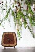 Larch branches decorated for Christmas above vintage alarm clock on table