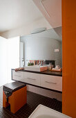 Washstand with countertop sink in bright bathroom with orange accents