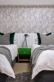Green bedside table between twin beds with continuous headboard in bedroom