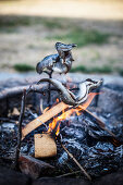 Grilled trout on a skewer over a campfire