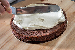 Spreading vanilla buttercream on a base of chocolate wedding cake