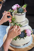 Baking a weddingcake with chocolate cake, vanilla butter cream and raspberrie filling, decorated with flowers