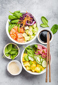 Two assorted poke bowls, raw tuna, salmon, vegetables, fruit