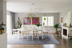 Designer chairs around white table in elegant dining room with fireplace