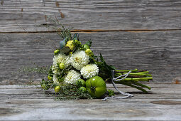 Bouquet of white pompom dahlias, grey santolina, houseleek rosettes and green tomatoes