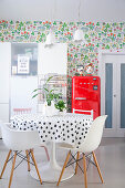 Essbereich, roter Kühlschrank und weißer Küchenschrank vor Blumentapete