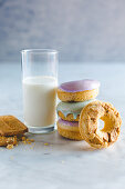A glass of milk with biscuits and donuts on a marble table