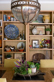 Pendant lamp with glass lampshade above dining table with shelves in background