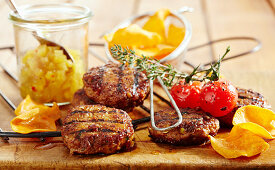 Grilled meat patties with pineapple chutney, cherry tomatoes and sweet potato crisps (Caribbean)