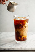 Eiskaffee in grossem Glas, Milch gerade hinzu gefügt