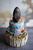A mini Easter cake topped with a peacock feather chocolate egg