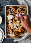 Drizzling sugar glaze over cinnamon rolls