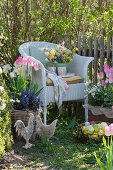 Wicker armchair with a spring bouquet between pots with spring plants on the garden fence decorated for Easter