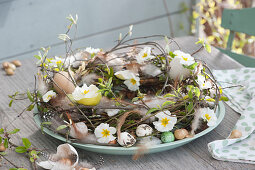 Easter wreath made of branches, decorated with primrose flowers, eggshells, feathers and onions