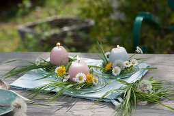 Small table decorations with Easter candles in flower wreaths